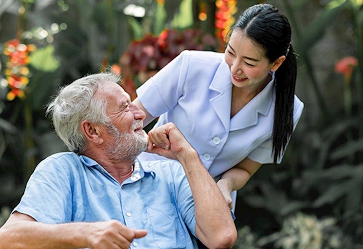 Volunteer helping a patient by pushing him in a wheel chair