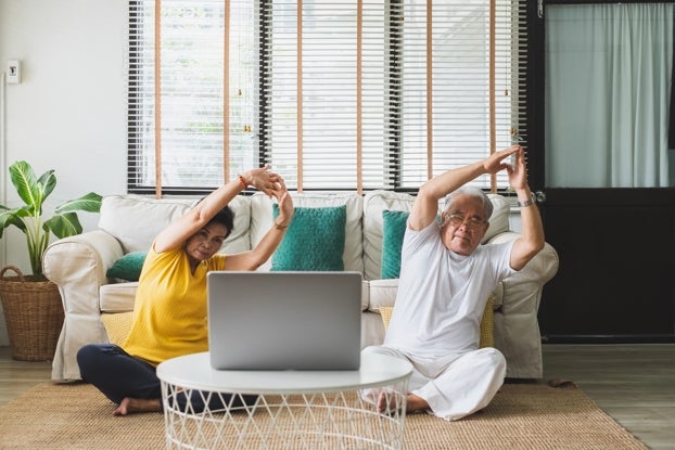 An older Asian couple performing Tai Chi on their living room floor